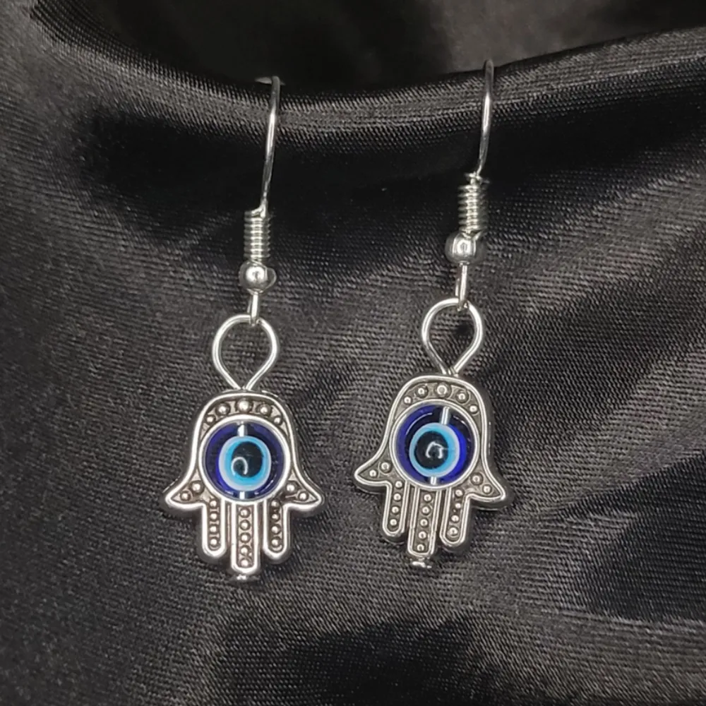Hamsa eller Fatimas hand är en uppmaning till oss själva att vara närvarande och älska oss som de vi är men symbolen skyddar även oss mot det onda ögat. Rostfritt! Troligtvis nickelfria men är du allergiker bör du vara försiktig.. Asusteet.