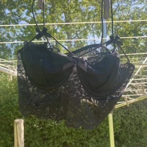 Svart spetts croptop - En svart spetts crop top med fina detaljer såsom små svarta rosetter och svarta snören. Fungerar som en vanlig ”Go out top” men även som en bralette. Knappt använd.  Storlek: S