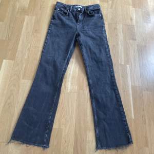 Mörkgrå/svarta utsvängda jeans som inte kommer till användning 