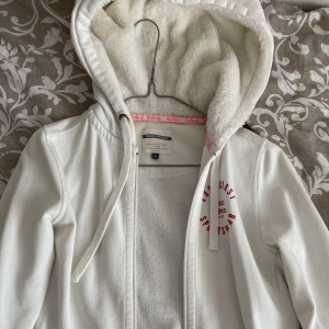 Vit kofta - Vit kofta med rosa detaljer och fluffig hoodie. Så mysig men säljs då den ej kmr till användning. Storlek 36❤️ sparsamt använd. 