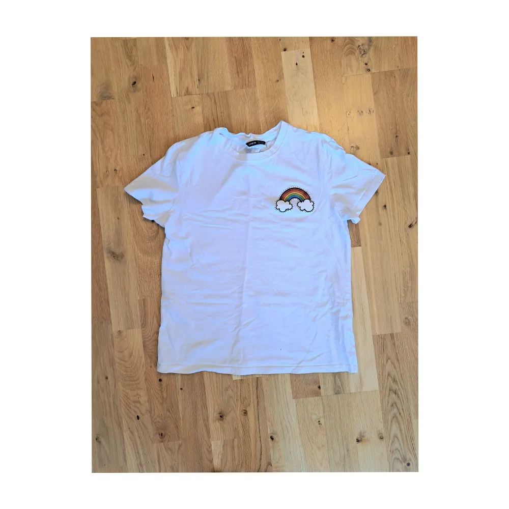 Fin, enkel, vit t-shirt med ett litet regnbågstryck på vänster bröst. Knappt använd. T-shirts.