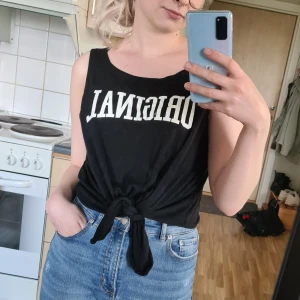 Svart topp - Topp med trycket "Original" på från H&M. Toppen knyts i änden och ger då en snygg passform. Lite nopprig på vissa ställen, men inget som syns.