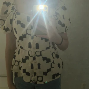Kortärmad blus  - Storlek: 36  Tröjan är i bra skick, ny tvättad samt i mode. Färgen är svart och mjölkvit/beige. 
