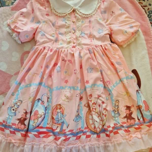 Alice in wonderland lolita klänning - Dragkedja vid sidan  Fodrad vid kjolen   2 Rosetter bak och fram  En av knapparna har börjat rosta lite men det går och byta ut till knapparna som finns där bak