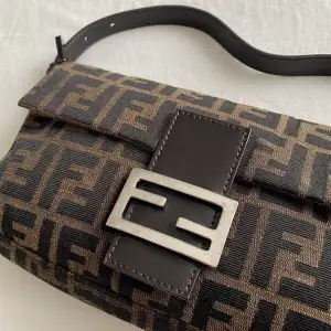 Fendi Zucca Baguette.  In excellent condition!  Vintage and 100% authentic.  Serial number, and FF stamped zipper hardware.  Tobacco and black FF monogram Zucca canvas.  Magnetized snap closure.  Slight discoloration on hardware. 