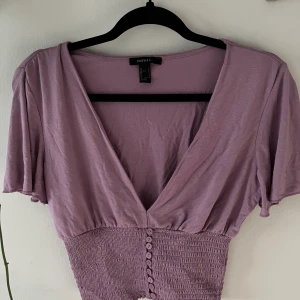 Lika topp från forever 21 - Lila topp köpt på forever 21 i beijing. Hur fin som helst och bra skick. Rätt urringad men kan skicka bild på det om de önskas. Annars jätteskönt tyg och flowy armar 