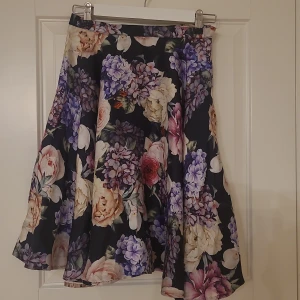 Vacker kjol - Vacker kjol med ett vackert blommönster. Tyget faller vackert runt benen. 