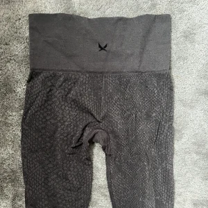 Gymtights - Snygga tights i mörkgrå färg med ormmönster. XXS stämmer verkligen inte då de är aningen stora på mig som har S. Väldigt stretchiga men formar fortfarande kroppen väldigt snyggt, tyvärr kommer de ej till användning. 