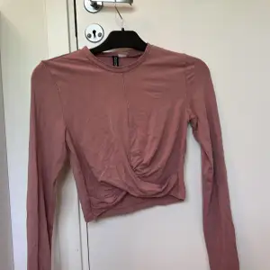 En kroppad långärmad tröja med fin modell på magen, i en rosa färg?  Väldigt söt och skönt, stretchigt material