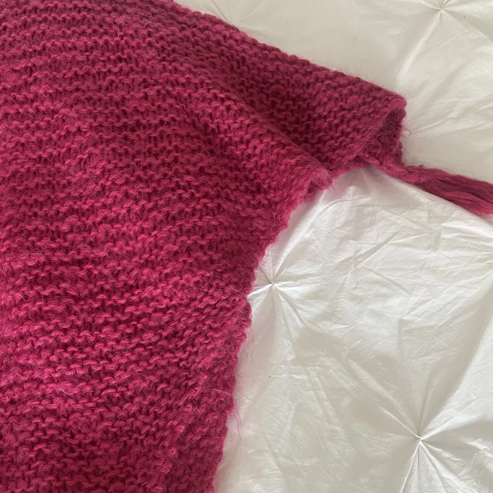 Hemstickad rosa poncho. Snyggt grov stickad med tofsar vid ärmarna, baktill och framtill. Resårstickad halskrage. . Övrigt.