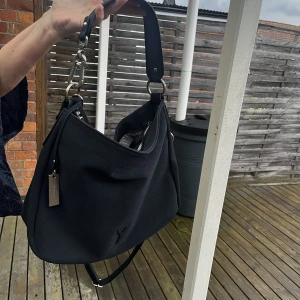 Väska  - Säljer min väska ifrån suri frey som är mörk blå. Inuti har den tre fack där två har dragkedja.   Är i bra skick. Köpte denna för 820kr och säljer för 400 Axelrämen kan man ta av. Höjd: 20 cm Vidd: 15cm Längd: 33cm   