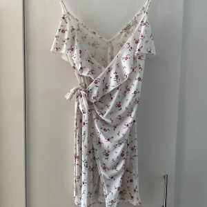 Klänning - Jättesöt omlott-klänning från Nelly. Vit med blommor på.