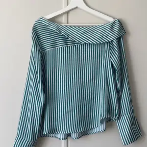 Grönvit randig blus. Den är smickrande offshoulder. Den är från Gina tricot i storlek 38