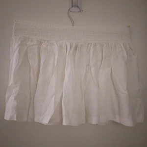 Vit kort kjol med stretchig bred resår i midjan, viskos, Strlk 36. Fint skick. - Vit kort kjol med bred mjuk resår med mycket stretch i midjan (jättebekvämt!). Material: Viskos. Strlk 36/SMALL. Fint skick. Helt felfri.