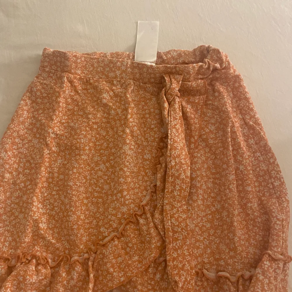 En blommig kjol typ orange användt ganska mycket men är i bra skick. Kjolar.