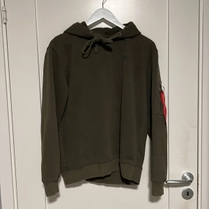 Alpha industrier hoodie - Storlek M Alpha industries hoodie fit med litet tryck på vänstra bröstkorgen. Kostade 620 kr som ny. Tveka inte att ställa frågor!  Detaljer på tröjan- Texten på röda bandet är lite slitet. 