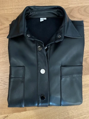 Svart skinnjacka - Supersnygg skinnjacka med silverknappar. Kan ha den öppen eller stängd. Knappt använd. Som ny.