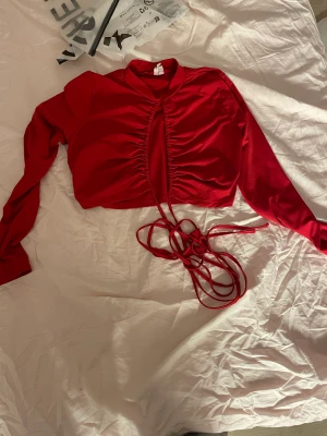 Röd topp med snörning - Lite turtuleneck, knytning under brösten. 