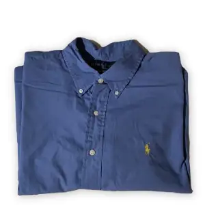 Blå Ralph Lauren skjorta, as snygg att använda som vanlig skjorta eller typ kofta över ett linne. Har en annan liknande skjorta så tänkte sälja av denna då ja ba använt den typ en gång, storlek XL 