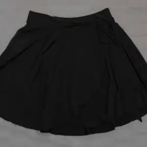 Svart kjol med knytdetalj från Shein. (Andra bilden är lånad). Relativt kort. Stretchigt material. Endast testad. Pris kan diskuteras privat!
