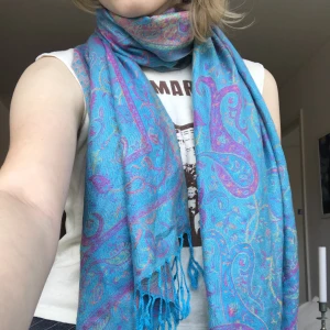 Hippie Sjal - En turkos sjal/halsduk/scarf i hippiestil! Mjukt och skönt tyg, värmer halsen så funkar bra som halsduk:-) turkos på utsidan och lila på insidan. kan mötas upp i stlhm