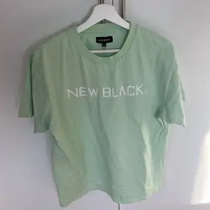  T-shirt ifrån new black. I bra skick och har en mint aktig färg.