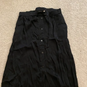 Svart kjol - Svart medellång kjol med knappar fram. Fint skick och inga tecken på användning. Storlek L från house of Lola men skulle säga att den passar en M också