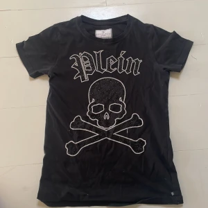 Philipp plein junior - Detta är en svart Philipp plein t- shirt som passar åldrar mellan 12-14 år gamla. Den har helt okej skick och ja säljer den för 999kr  medans den kostar några tusen nypris 