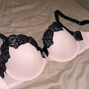 Bh i storlek 70E💕 - Säljer denna jättefina helt oanvända ljusrosa bhn med svart spets från hunkemöller då den tyvärr inte passar mig. Storleken är 70E. Pris är 180kr+frakt💗💕