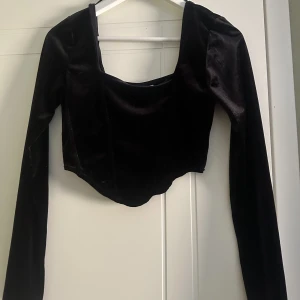 Fin långärmad topp  - Säljer min korta, svarta långärmade topp i sammetstyg. Den är urringad både fram o bak med silikontejp framtill för bättre passform. Passar bra nu på sommaren. 