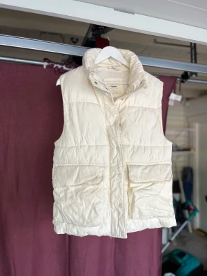 Vit Dunväst - Nyskick, och superskönt material. Väldigt oversized med tanke på storleken, men sätter sig snyggt på! Mer gräddvit än klarvit i nyansen, skriv för mer bilder (på). 