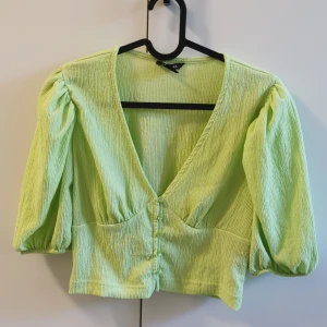 Tröja Monki stl S - Grön festlig topp med puffärmar från Monki. Lite glansig i tyget (se bild 2). Kommer inte till användning så bättre att den får hitta nytt hem 🥰