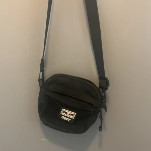 Liten crossbodyväska  - En svart crossbody väska. Med flera fack och innerfickor. Inställbar längd på remmarna. 