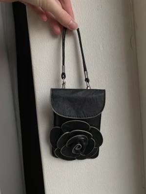 Väska med blomma  - Säljer denna lilla väska. Fint skick och medföljer två olika band ett längre och ett kortare💕