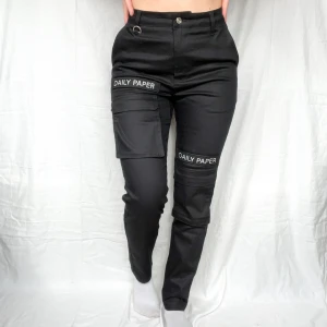 Cargobyxor från Daily Paper - Cargobyxor från Daily Paper i strl S. Märkerna på framsidan med texten ”Daily Paper” går att ta bort då de fästs med kardborreband. Så snygga!