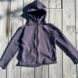 Houdini fleece  - En lila Houdini fleece i perfekt skick. Dragkedjan har lossnat och erkänts med en nyckelring med funkar lika bra 💖. Storlek 140. Pris 350kr.💕 