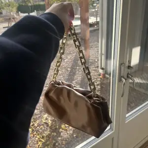 En brun väska med guld kedja 