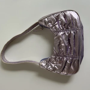 Handväska - Superfin baugetteväska i en skrynlig modell!!  Från monki, en perfekt festväska för att klä upp en outfit!