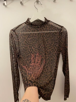 Top  - En genomskinlig transparent animal print tröja i storlek XS. Denna stilfulla tröja har använts sparsamt och är i utmärkt skick. Den har en unik design med djurtryck, perfekt för att skapa en trendig och vågad look.
