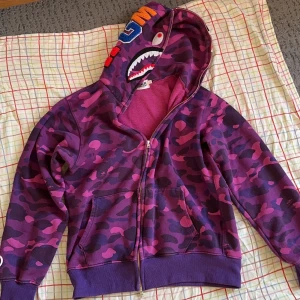 Lila Bape Hoodie - Inte äkta. Väldigt bra kvalitet. Strl L men passar strl S. (Liten i storleken) Jag är 172 cm lång och den passar prima! Om du vill ha fler bilder på tröjan, skriv till mig så fixar jag det 💪🏼