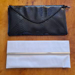 Två clutch väskor, en vit 30x13cm, och en svart 30x17cm. Priset är för båda, annars 45 for var