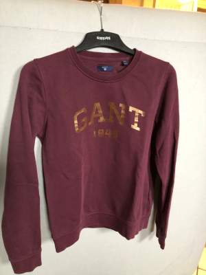Vinröd äkta Gant tröja med guld detaljer. Använd två-tre gånger. Gjord av 87% bomull och 13% polyester. Säljs då det inte är min stil längre. Kommer från ett rökfritt hem.