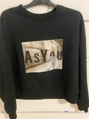 Tröja  - En svart långärmad tröja med tryck på framsidan 