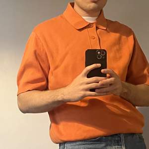 Hi! A short sleeved orange polo from COS. It is a small but fits a medium.  Only worn once and it is made of 100% cotton.