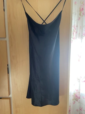 Svart satin klänning  - Svart kort satin klänning med Criss cross på ryggen. Använd få tal gånger, väldigt fint skick 