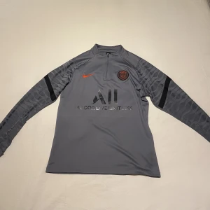 PSG Tracksuit - Grå/Röd PSG tracksuit i jätte bra skick, använt fåtal gånger. Säljer då de it riktigt passar mig. Både toppen och byxorna är i storlek M.