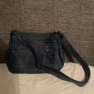 Väska - Liten jeansfärgad blå väska med många olika fickor.