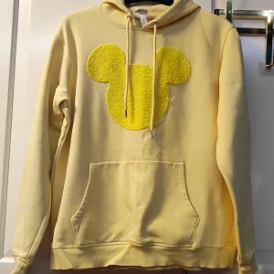 Gul Disney Hoodie - Väl använd hoodie men i bra skick. Stor Musse pigg siluett i mitten.