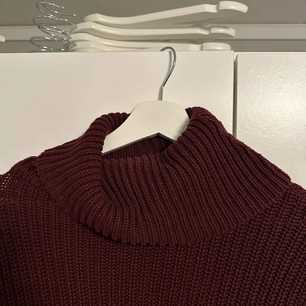 En jättefin stickad vinröd tröja med en löst sittande polokrage som är anings kortare än en vanlig tröja. Tröjan är använd men inget som märks. Tröjor & Koftor.