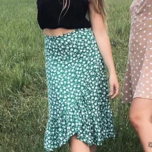 Kjol - Vacker blommönstrad volangkjol. Perfekt till midsommar! Diskret dragkedja i sidosömn vid midjan. Strl 36, half waist 36 cm, använd ett fåtal ggr. 